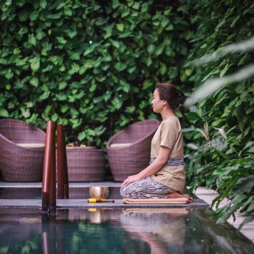a woman sitting in meditation near a pool of water at Alba Spa Hotel in Hue