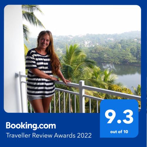 a woman in a striped dress standing on a balcony at Mahaweli View Inn in Kandy