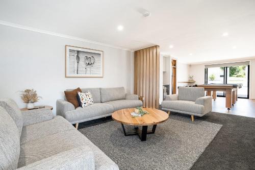 a living room with two couches and a table at Beach Walk on Alfred in Bridport
