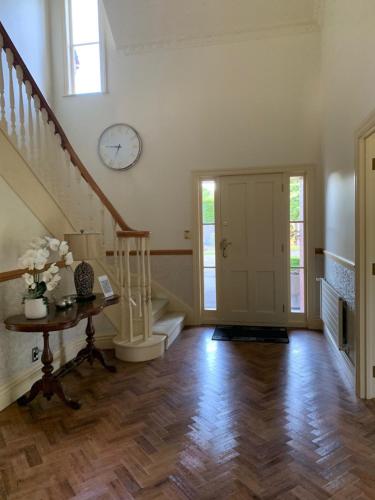 a living room with a staircase and a clock on the wall at Pin Oaks Luxury Bed & Breakfast in Palmerston North