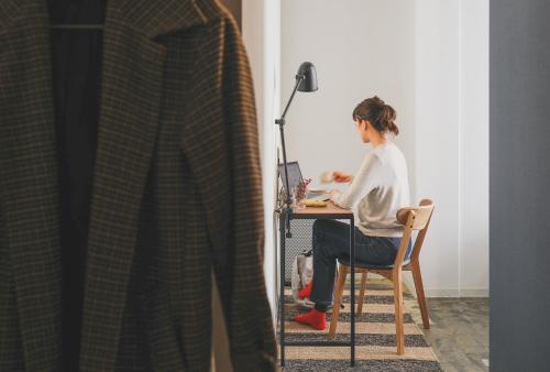 a woman sitting at a desk with a computer at Hostel Niniroom in Kyoto