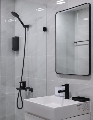 a white bathroom with a sink and a mirror at Tzu Chi Hotel in Pingtung City