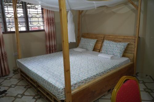 a bedroom with a wooden bed with a canopy at L&J Modern Backpackers Kinondoni in Dar es Salaam