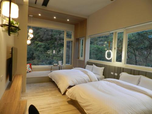 Dos camas en una habitación con dos ventanas. en 谷關明高溫泉 Mingao Hot Spring Resort, en Heping