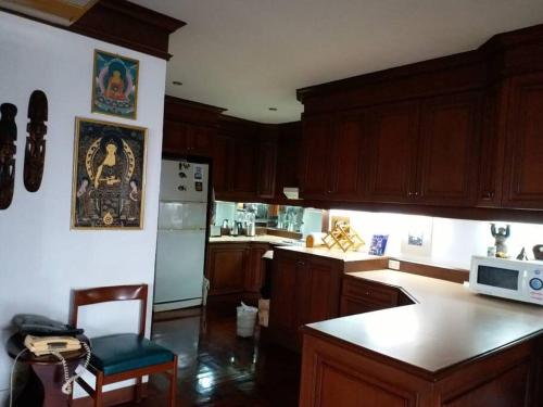 a kitchen with wooden cabinets and a white refrigerator at Stunning 24th Fl Terrace Penthouse! in Bangkok
