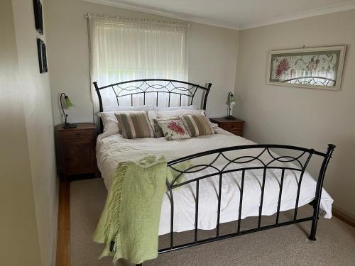 Dormitorio con cama con marco negro y ventana en The Little House on The Hill, en Badger Creek