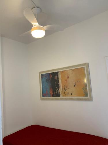 a painting on a white wall with a ceiling fan at Adolfo Paiva Apartment in Rio de Janeiro