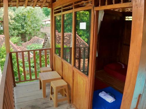 a wooden cabin with a bench on a balcony at Wisma Pancoeran in Grigak