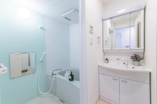 a white bathroom with a shower and a sink at SHINJUKU Residence BLDG in Tokyo