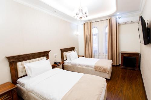 a hotel room with two beds and a television at Hotel Silver Rows in Samarkand