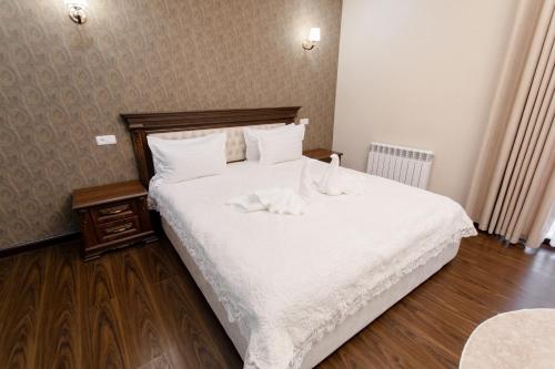 a bedroom with a large white bed with white sheets at Hotel Silver Rows in Samarkand