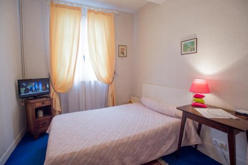 a small bedroom with a bed and a television at Hôtel Saint Vincent in Bagnères-de-Bigorre