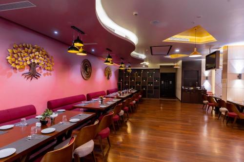 a dining room with long tables and red walls at Vivanta Jamshedpur, Golmuri in Jamshedpur