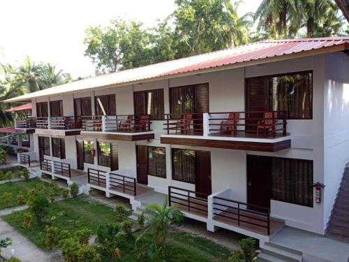 an apartment building with balconies and tables and chairs at Coconhuts Beach Resort in Neil Island