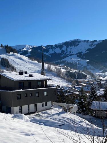 a snow covered town with a church and a mountain at Bergleben Maria Alm - Haus Panorama in Maria Alm am Steinernen Meer