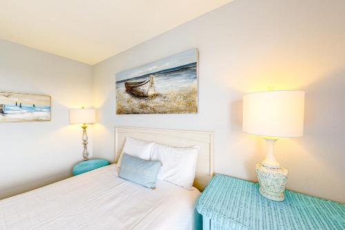a bedroom with a bed with a lamp and a chair at Grand Caribbean #216 - Sandy Restoration in Orange Beach