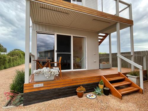 a house with a wooden deck with a patio at Boat Harbour Jetty B&B in Port Albert