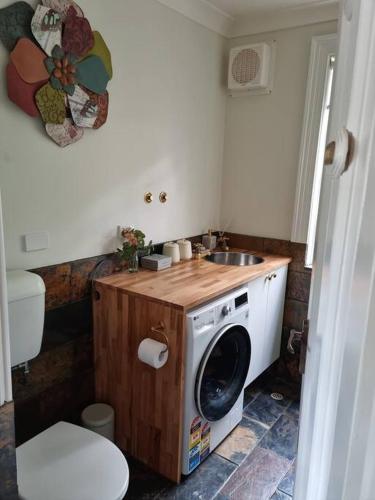 a bathroom with a washing machine and a sink at Historic Mintaro Post Office in Mintaro