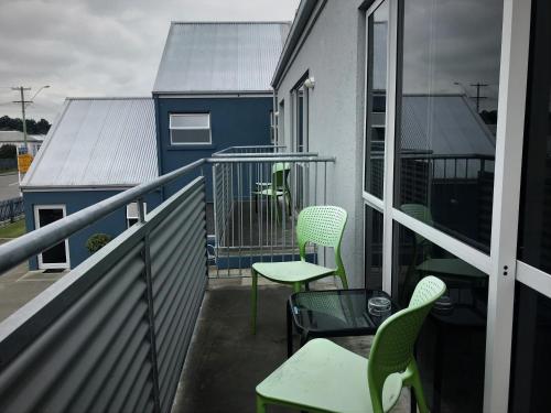 a balcony with chairs and tables and a blue building at Phoenix Motels in Temuka