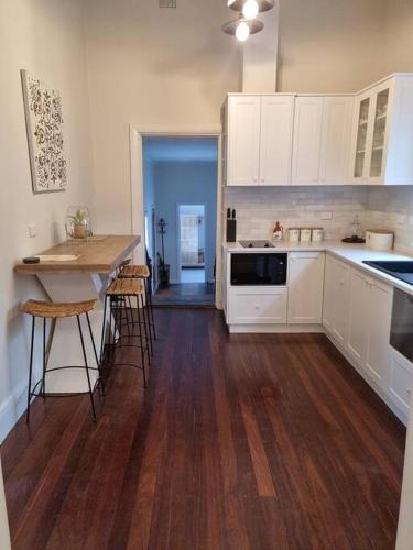 a kitchen with white cabinets and a wooden floor at Historic Mintaro Post Office in Mintaro