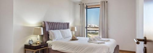 a bedroom with a bed and a window with a view at Sunset Home Olhão- Modern 3 bed Luxury Apartment with rooftop pool in Olhão