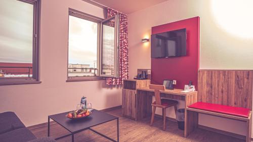 a living room with a couch and a desk with a tv at DAS HÜRNER in Ansbach