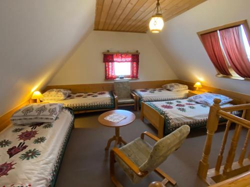 ザコパネにあるDomki Camping Harendaのベッド3台、テーブル、椅子が備わる客室です。