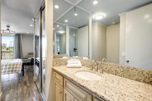 um banheiro com uma pia e um espelho grande em Modern condo with access to pool & hot tub in great location em Oceanside