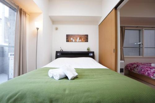 a bedroom with a large green bed with towels on it at 長期割引 豊水すすきの駅からすぐ IK Minami 6 Jo Residence 803 IK南6条レジデンス in Sapporo