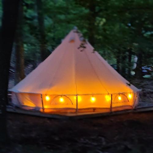 a white tent with lights in the woods at Naturglamping in Kristianstad