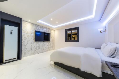 a bedroom with a white bed and a tv on a wall at Seosan Aria Hotel in Seosan