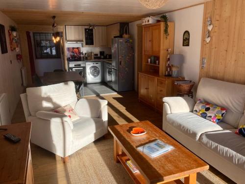 a living room with two white couches and a kitchen at Chalet Cyclamens- 65m2 plein centre des Carroz - WIFI & parking! in Les Carroz d'Araches