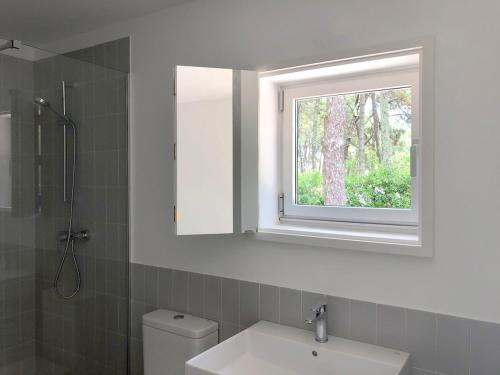 baño con lavabo, espejo y ventana en Apartamentos Camping Coroso en Ribeira