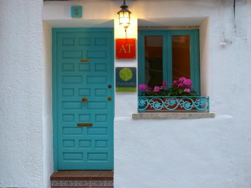 a blue door and a window with flowers in a window box at Casco Viejo Candeleda in Candeleda