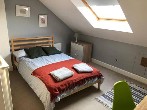 um quarto com uma cama com um cobertor vermelho e uma clarabóia em Twickes Townhouse em Londres