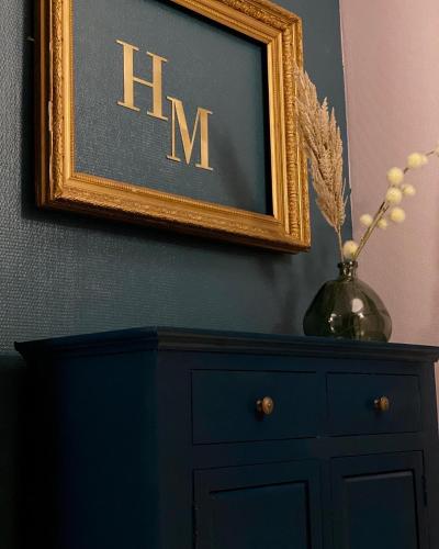 a black dresser and a picture with the letter m on it at Hotel Le Midi Clermont-Cournon in Cournon-dʼAuvergne