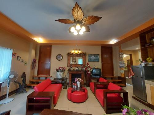 una sala de estar con muebles de color rojo y una lámpara de araña. en Dahilayan Comfy Cabin, en Manolo Fortich