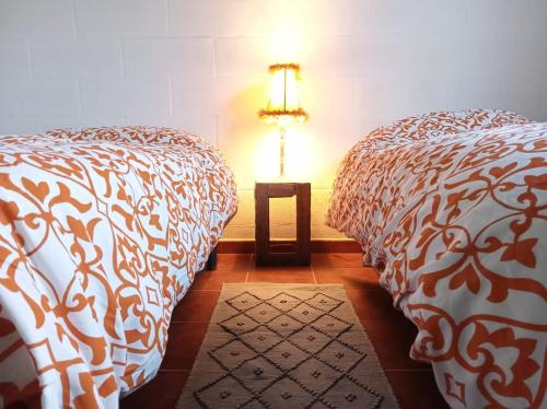 duas camas num quarto com um candeeiro sobre uma mesa em La Bodega de Villa Bella em Espartinas