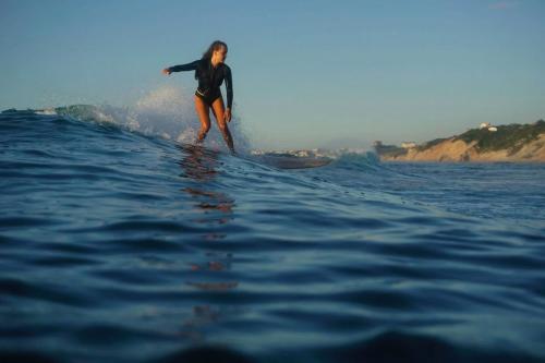 a woman riding a wave on a surfboard in the ocean at Villa Anvers Guethary in Bidart