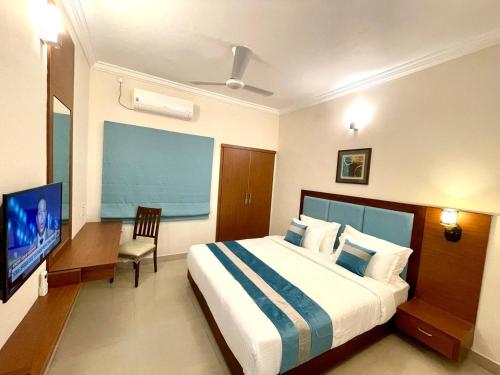 a bedroom with a bed and a desk and a television at The Oval House, Kochi - Approved by Kerala Tourism - Exclusively for Families in Cochin