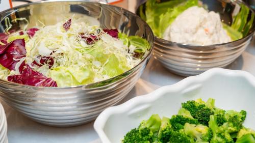 a table with two bowls of salad and a plate of broccoli at ibis Budget Osaka Umeda in Osaka