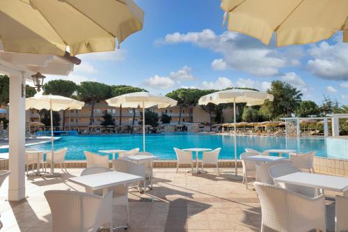a pool with tables and chairs and umbrellas at Tirreno Resort in Cala Liberotto