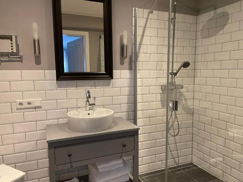 a white bathroom with a sink and a shower at Friesen-Lodge Ferienwohnungen in Breklum