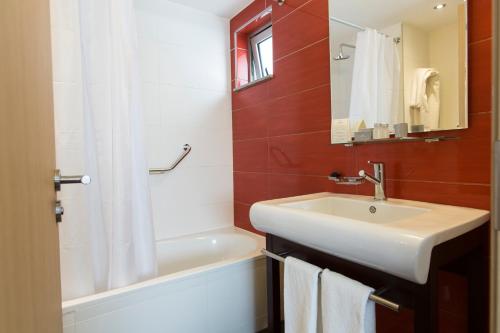 uma casa de banho com um lavatório, um chuveiro e uma banheira em Regency Way Montevideo Hotel em Montevidéu
