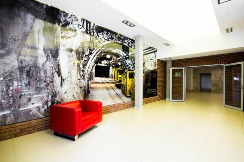 a red chair in a hallway with a wall mural at Park Hotel Diament Zabrze - Gliwice in Zabrze
