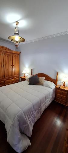ein Schlafzimmer mit einem großen weißen Bett und zwei Nachttischen in der Unterkunft Apartamentos Tesón Ribadeo in Ribadeo