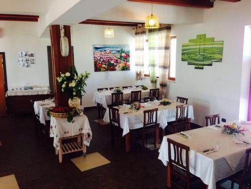 モルフェッタにあるAgriturismo La Ferroviaの白いテーブルと椅子(花付)が備わるレストラン