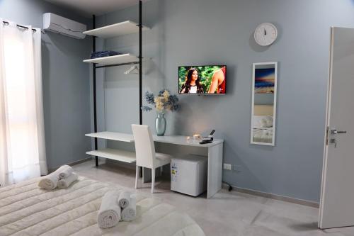 1 dormitorio con 1 cama, escritorio y TV en B&B La Nuit en Agrigento