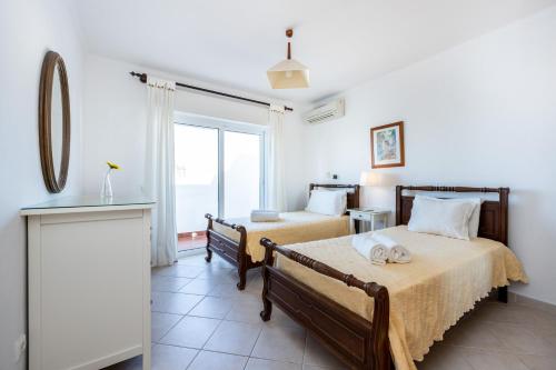 een slaapkamer met 2 bedden en een raam bij Villa dos Netos in Albufeira