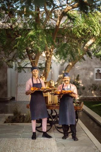 two women holding plates of food in front of a table at Six Senses Fort Barwara Sawai Madhopur in Sawāi Mādhopur